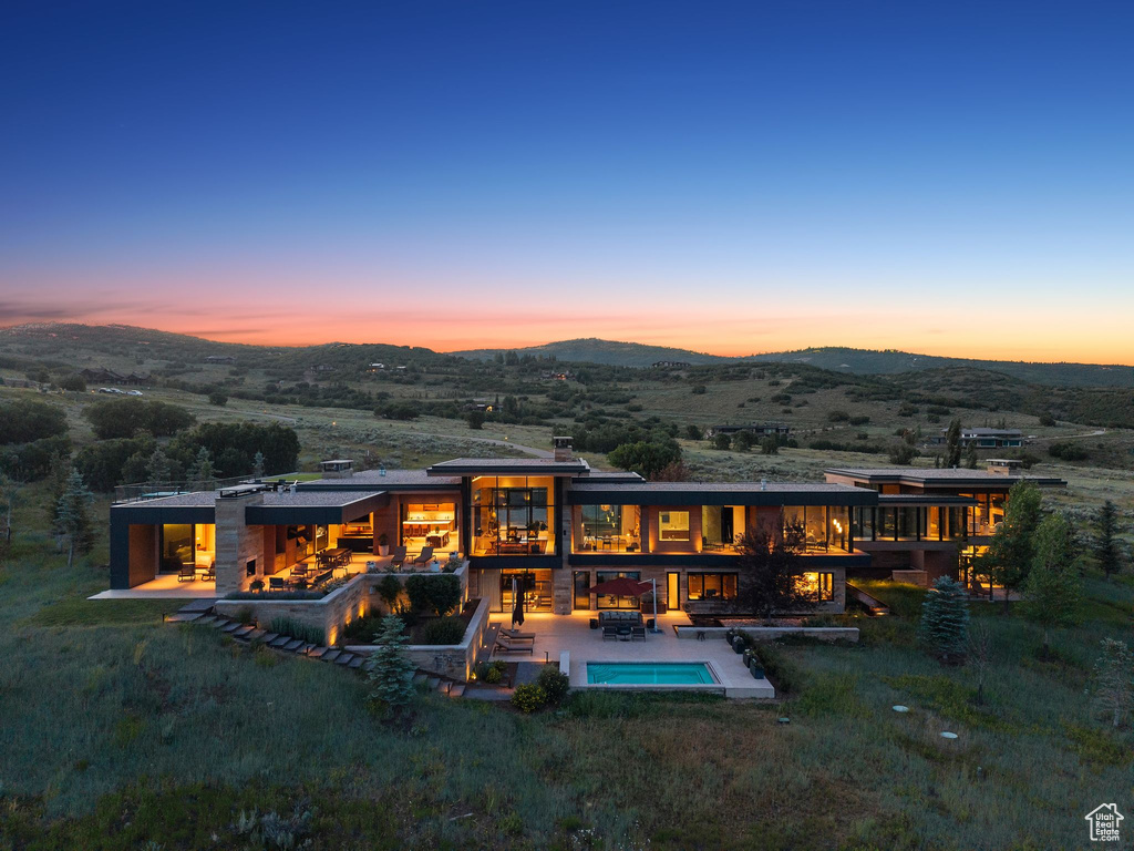Back of house with a mountain view, a patio area, an outdoor pool, and a balcony