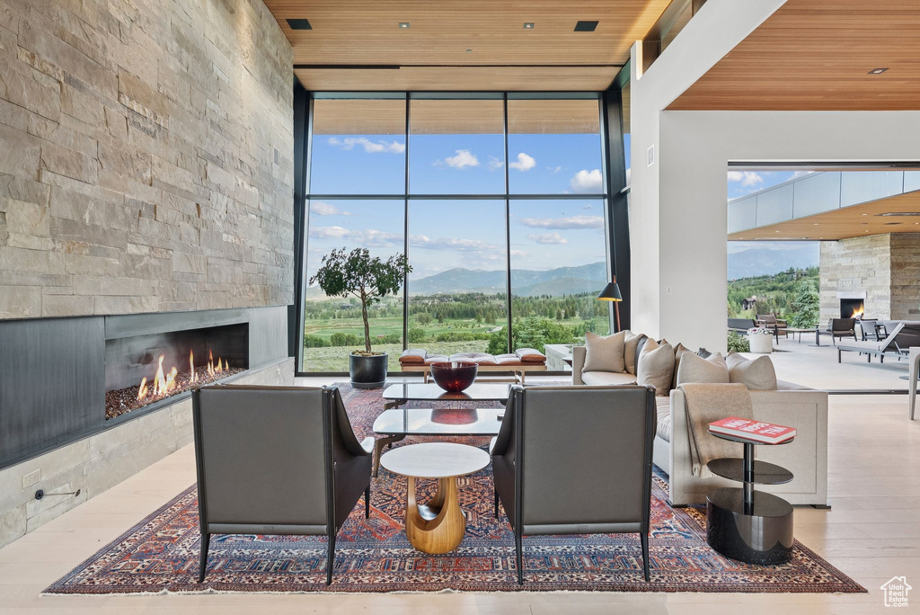 Living area featuring a large fireplace, expansive windows, a mountain view, wood ceiling, and plenty of natural light