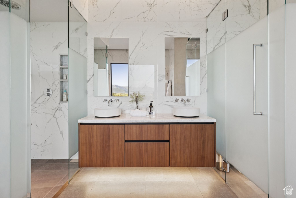 Bathroom featuring double vanity and a marble finish shower