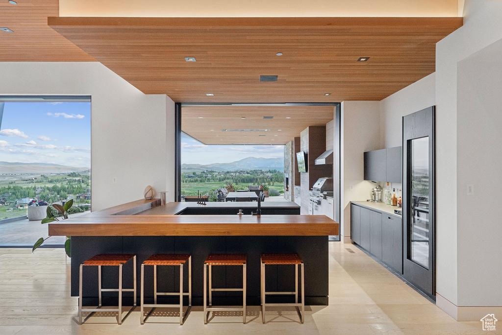 Kitchen featuring wooden ceiling, healthy amount of natural light, a kitchen bar, a mountain view, and recessed lighting