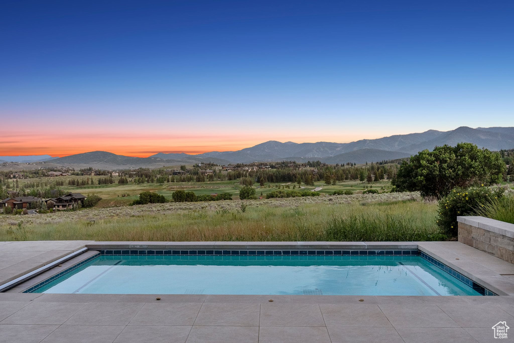 Pool at dusk featuring a mountain view and an outdoor pool