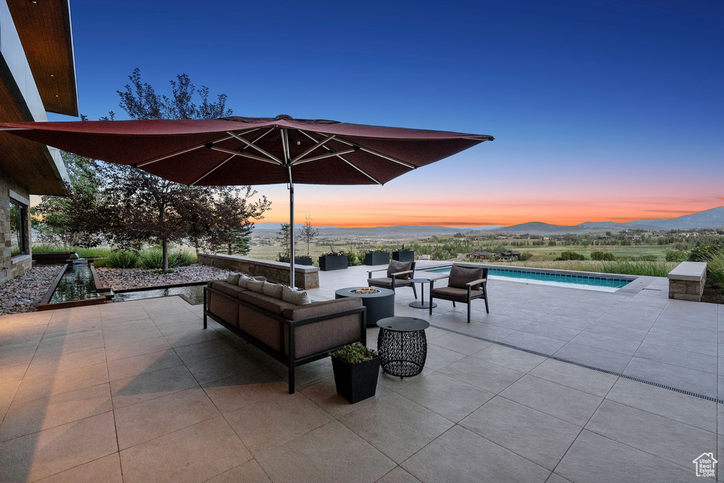 View of patio / terrace featuring an outdoor pool, an outdoor living space with a fire pit, and a mountain view