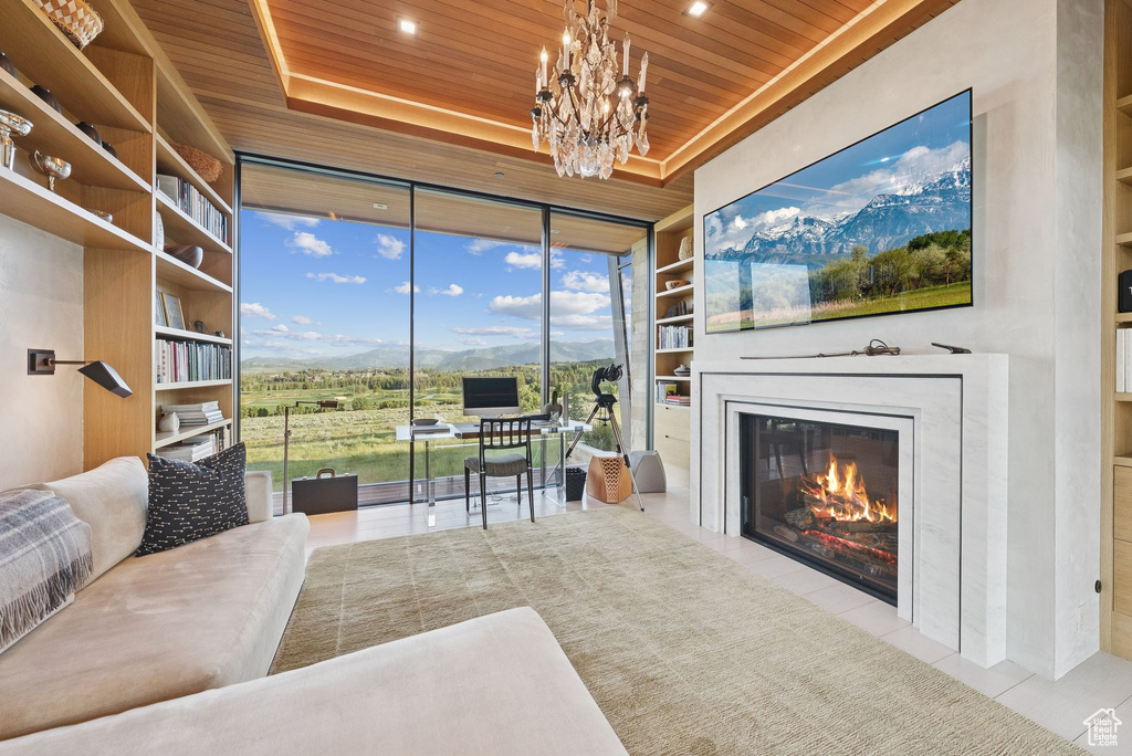 Tiled living room with wooden ceiling, a chandelier, a fireplace with flush hearth, built in shelves, and a raised ceiling