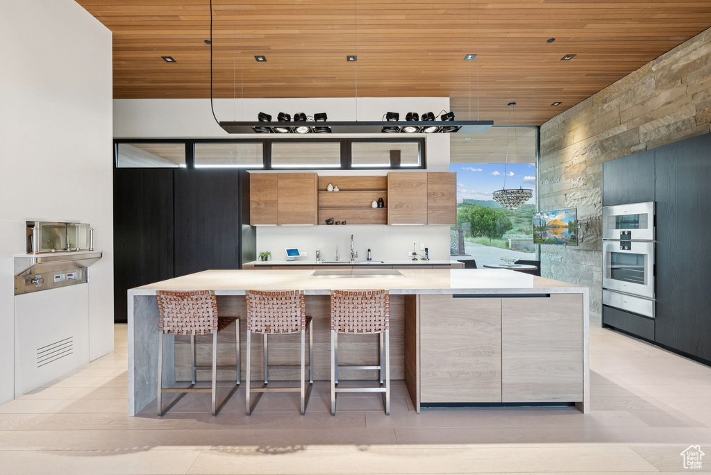 Kitchen with wood ceiling, open shelves, modern cabinets, light countertops, and a kitchen bar