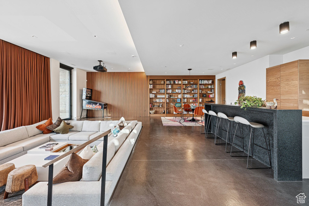 Living area featuring built in features, finished concrete flooring, and wooden walls