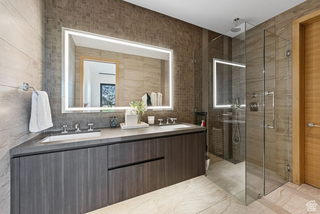Bathroom with a stall shower, tile walls, and double vanity