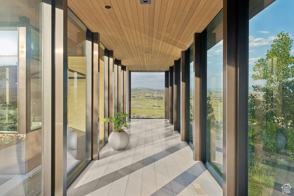Unfurnished sunroom featuring expansive windows, tile patterned floors, and wood ceiling