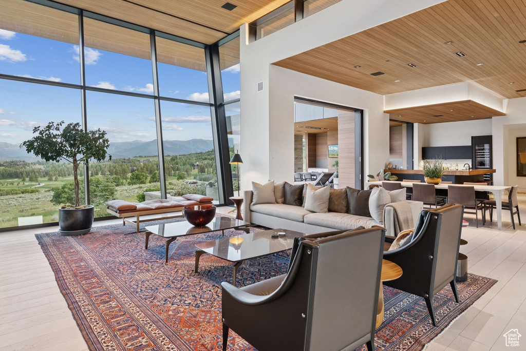 Living room with floor to ceiling windows, a mountain view, wooden ceiling, and wood finished floors