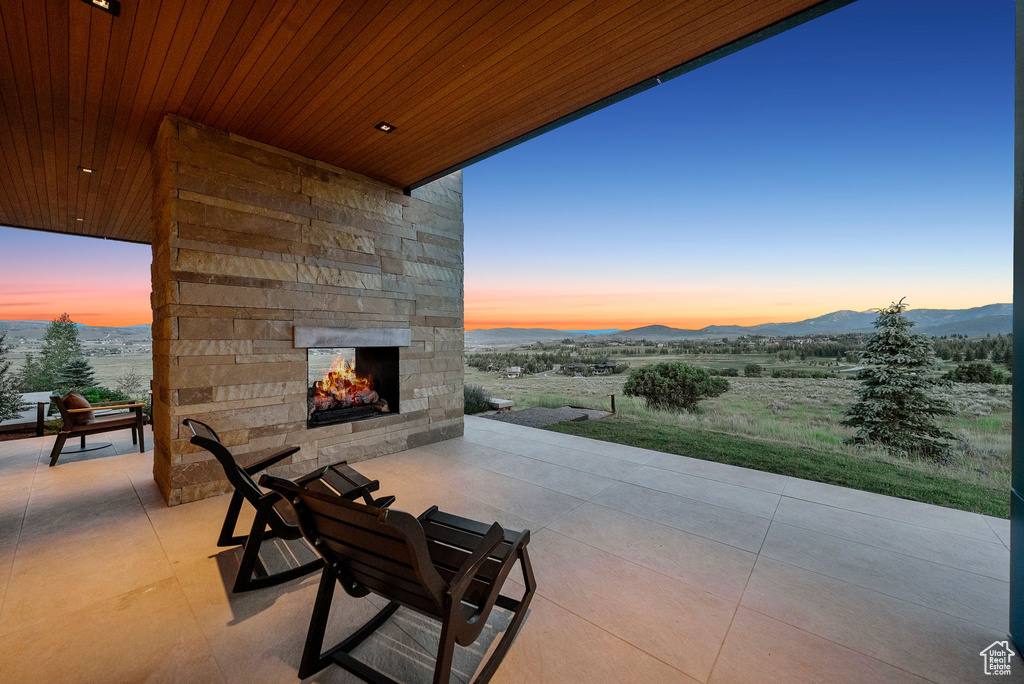 View of patio featuring an outdoor stone fireplace and a mountain view
