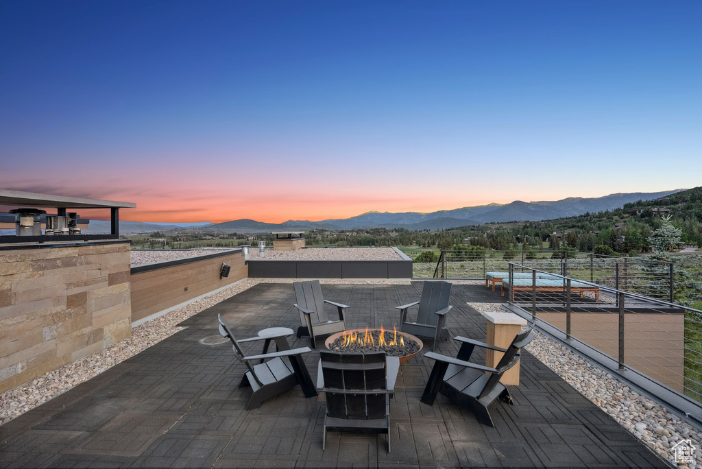 Patio terrace at dusk featuring a mountain view, a fire pit, and a patio area