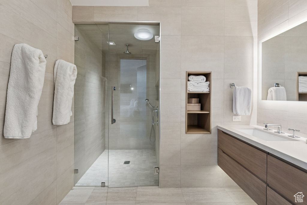 Full bathroom with tile walls, vanity, a stall shower, and tile patterned flooring