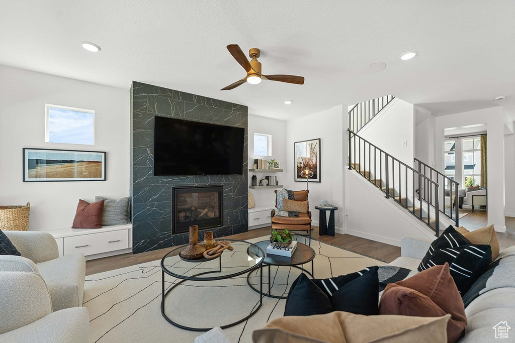 Living area featuring wood finished floors, stairs, a ceiling fan, a premium fireplace, and recessed lighting