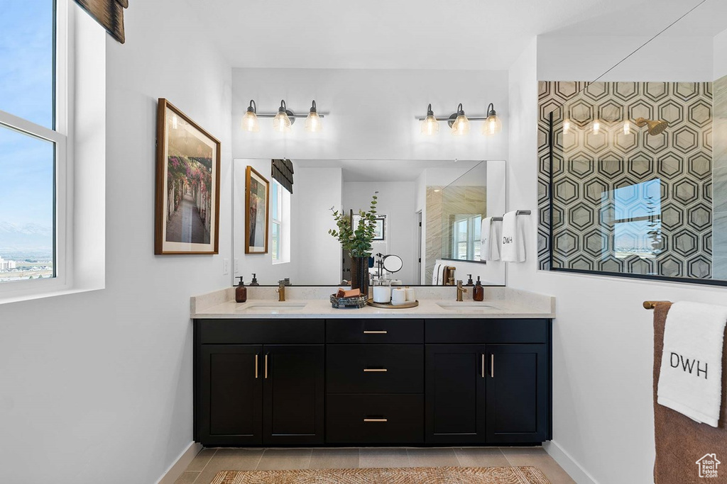 Full bath featuring double vanity, plenty of natural light, and a tile shower
