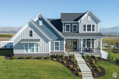 Modern farmhouse featuring board and batten siding, a front yard, a mountain view, and covered porch