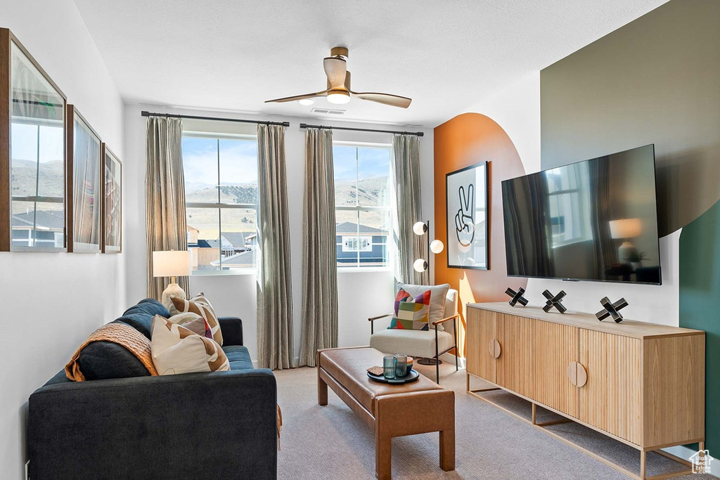 Carpeted living room with a ceiling fan