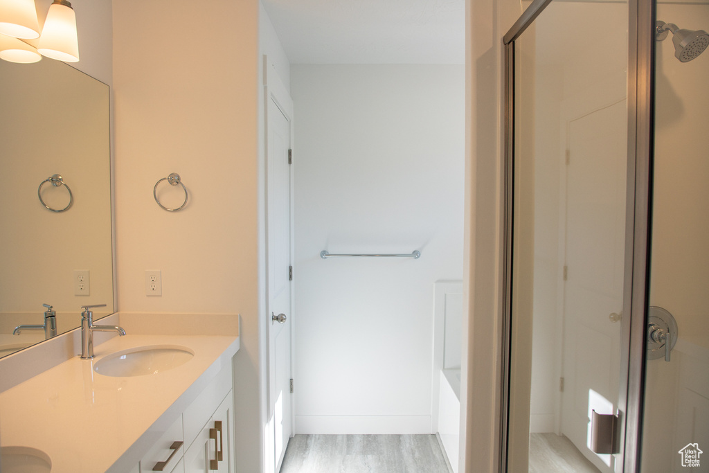 Bathroom featuring double vanity, an enclosed shower, and wood finished floors