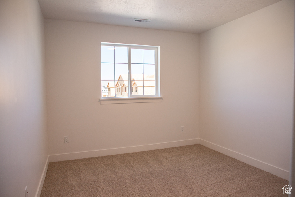 Spare room featuring carpet flooring and baseboards
