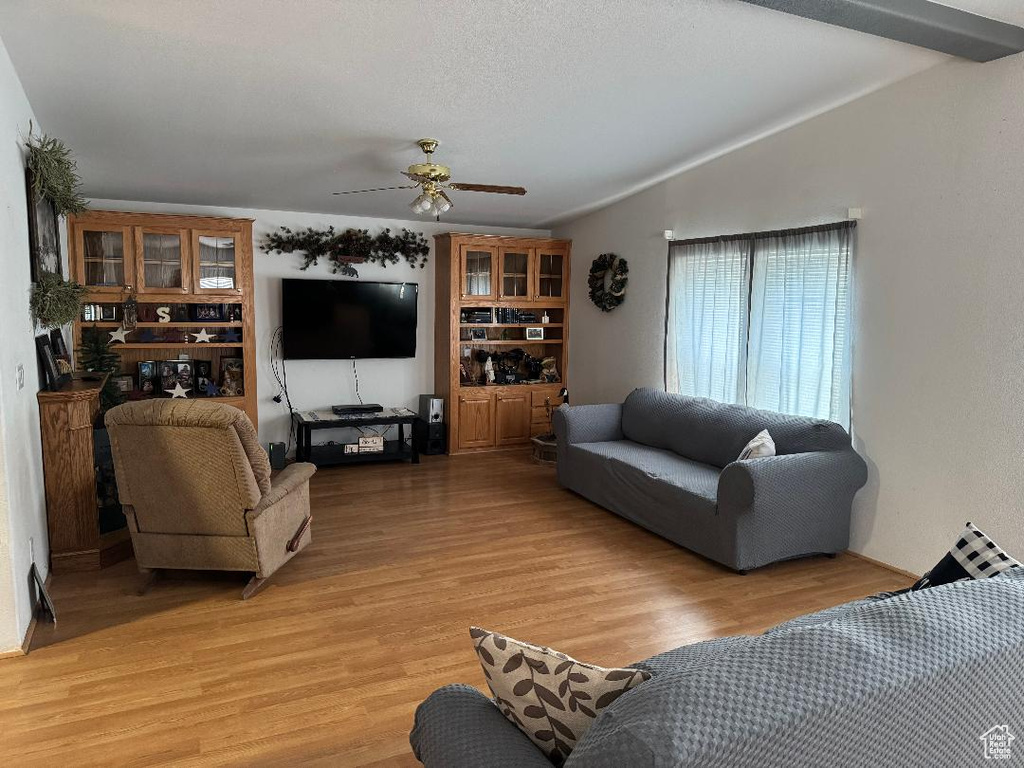 Living room with ceiling fan, light wood-type flooring, and vaulted ceiling