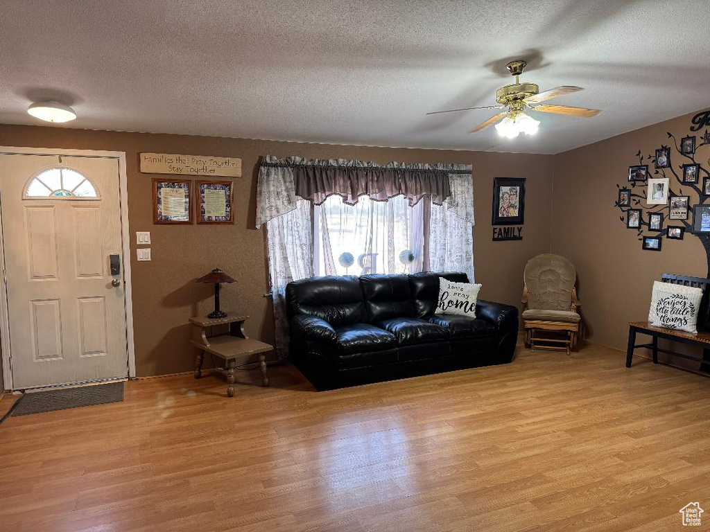Living area with light wood-style floors, ceiling fan, and a textured ceiling