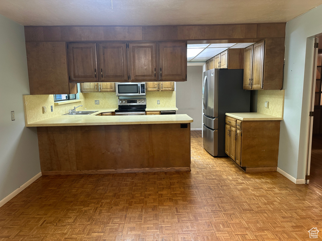 Kitchen with stainless steel appliances, light countertops, backsplash, and a peninsula