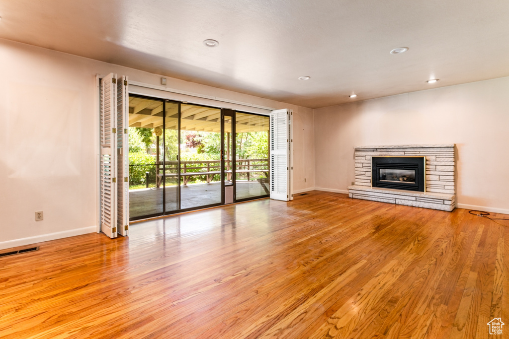 Unfurnished living room with wood finished floors, recessed lighting, and a fireplace