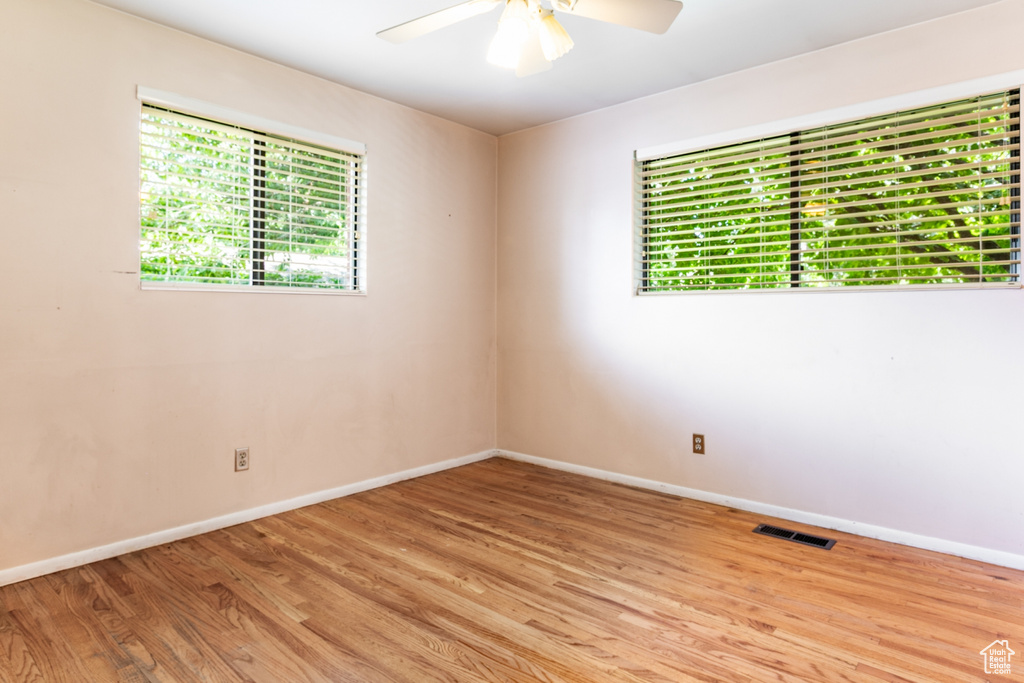 Empty room with ceiling fan and light wood finished floors