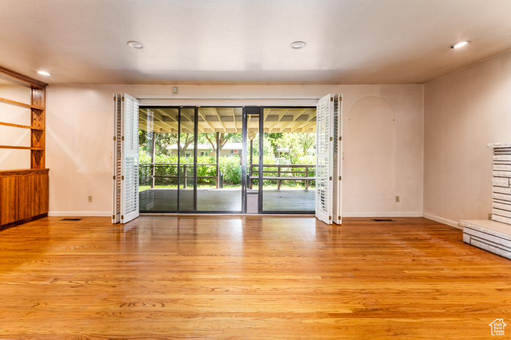 Unfurnished living room with light wood-style flooring, recessed lighting, a stone fireplace, and arched walkways