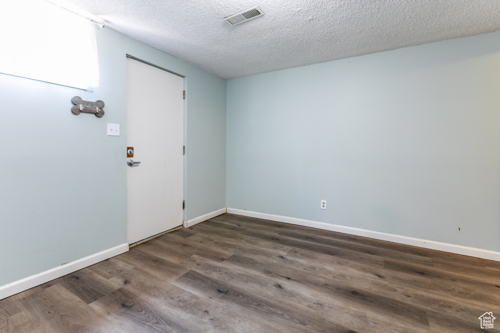 Unfurnished room with dark wood finished floors and a textured ceiling