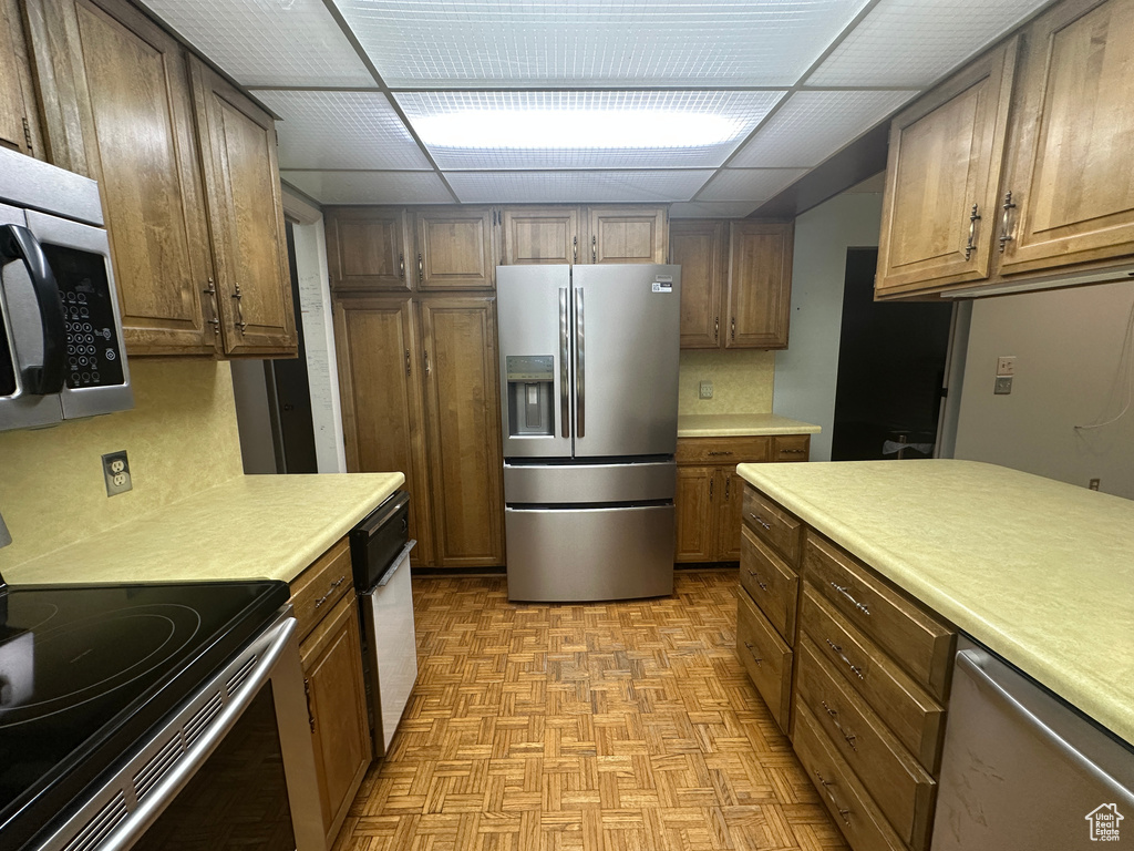 Kitchen featuring appliances with stainless steel finishes, light countertops, light floors, and a paneled ceiling
