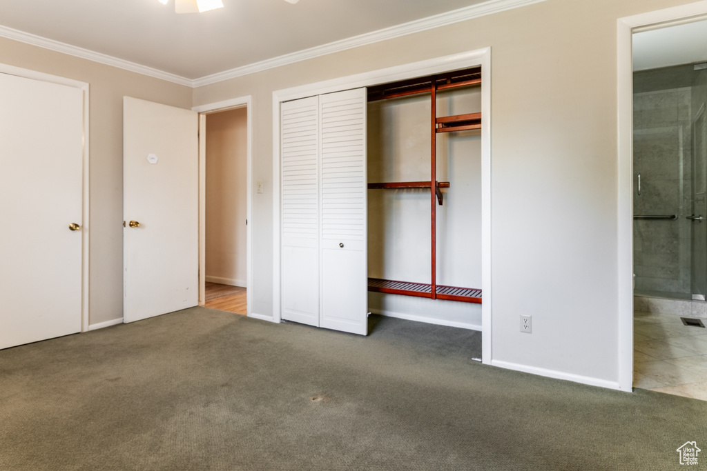 Unfurnished bedroom featuring crown molding, carpet floors, ensuite bath, and a closet