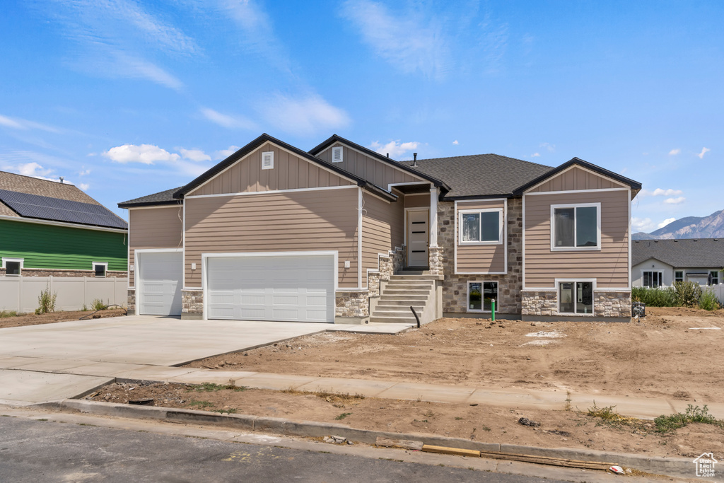 Craftsman inspired home with stone siding, concrete driveway, an attached garage, and board and batten siding