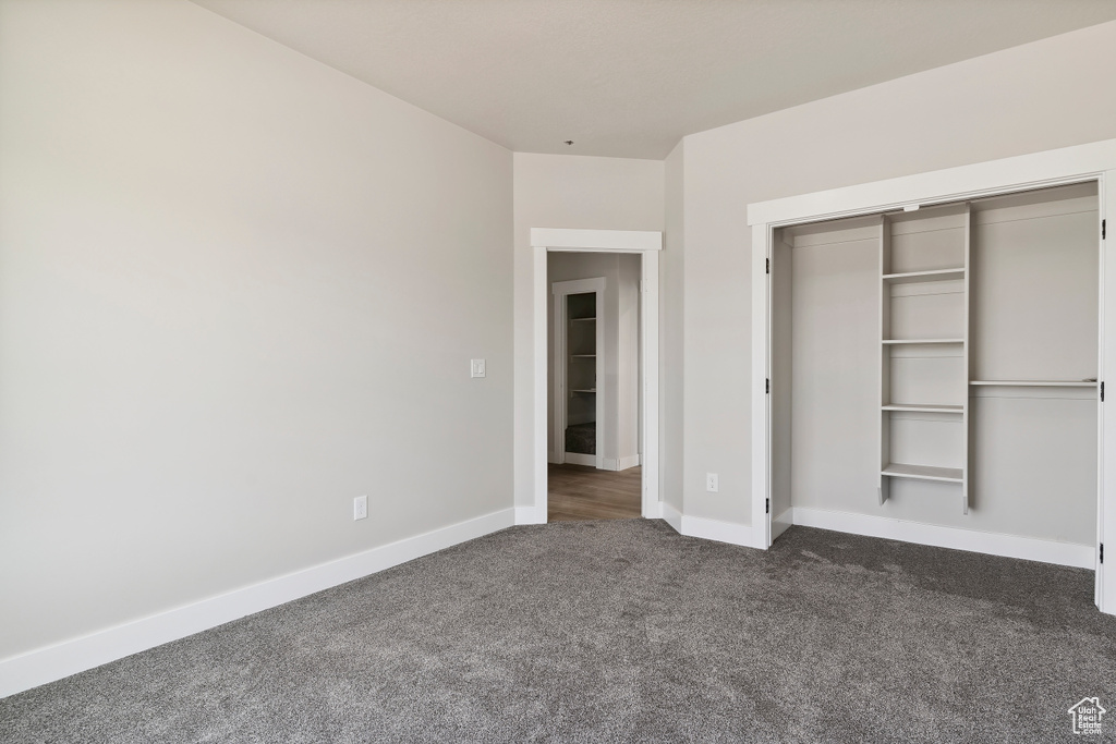 Unfurnished bedroom featuring dark colored carpet and a closet