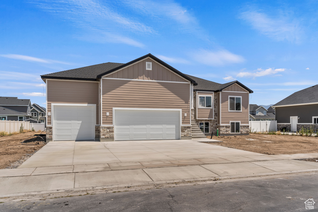 Craftsman inspired home featuring stone siding, an attached garage, concrete driveway, and board and batten siding