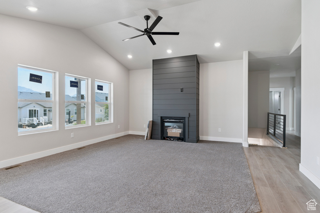 Unfurnished living room with a large fireplace, a ceiling fan, vaulted ceiling, light wood finished floors, and recessed lighting
