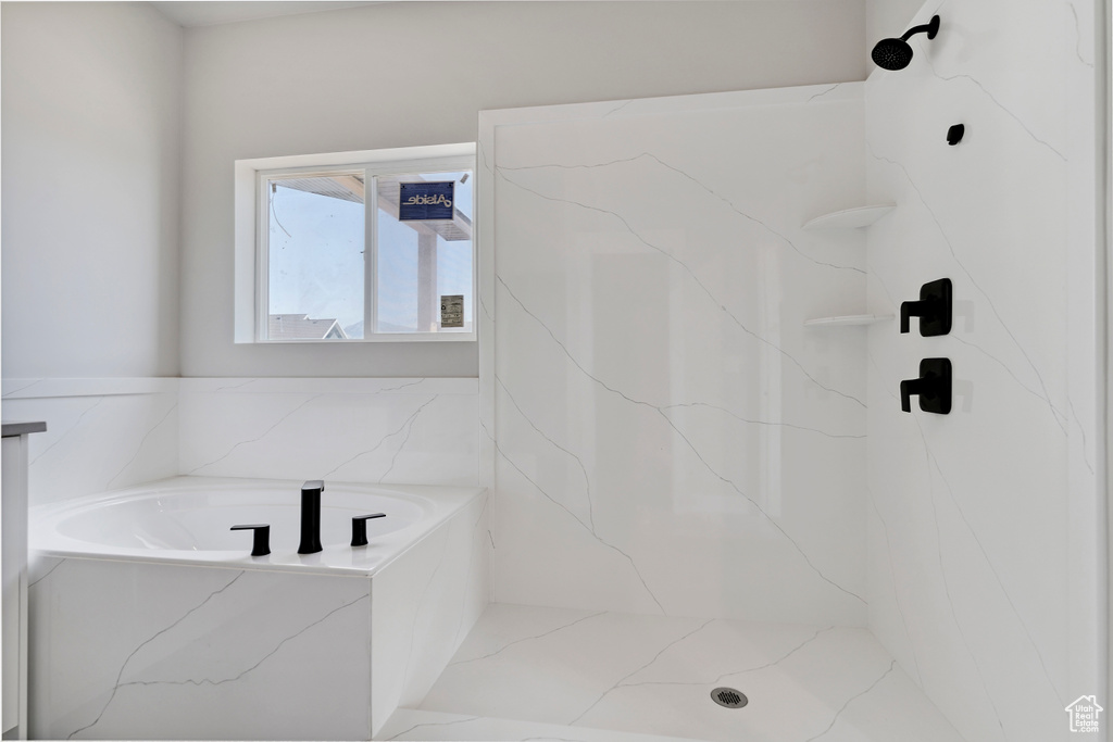 Bathroom with a marble finish shower and a garden tub
