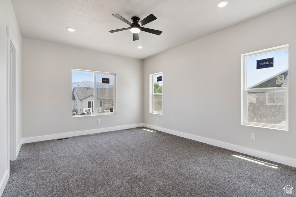 Carpeted empty room with plenty of natural light, ceiling fan, and recessed lighting