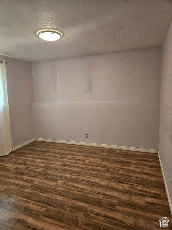 Unfurnished room with dark wood-style flooring and a textured ceiling