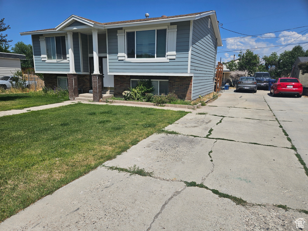 Raised ranch with a front yard, brick siding, and driveway