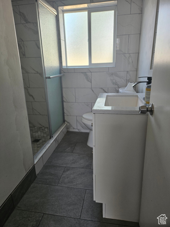 Full bath with vanity, a stall shower, and tile walls