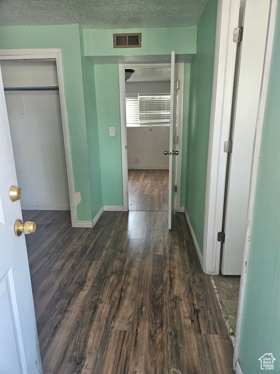 Unfurnished bedroom with dark wood-style flooring, a closet, and a textured ceiling