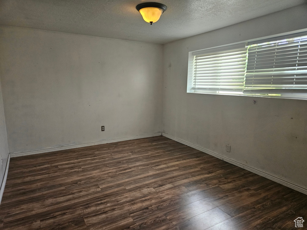 Empty room with dark wood-type flooring and a textured ceiling