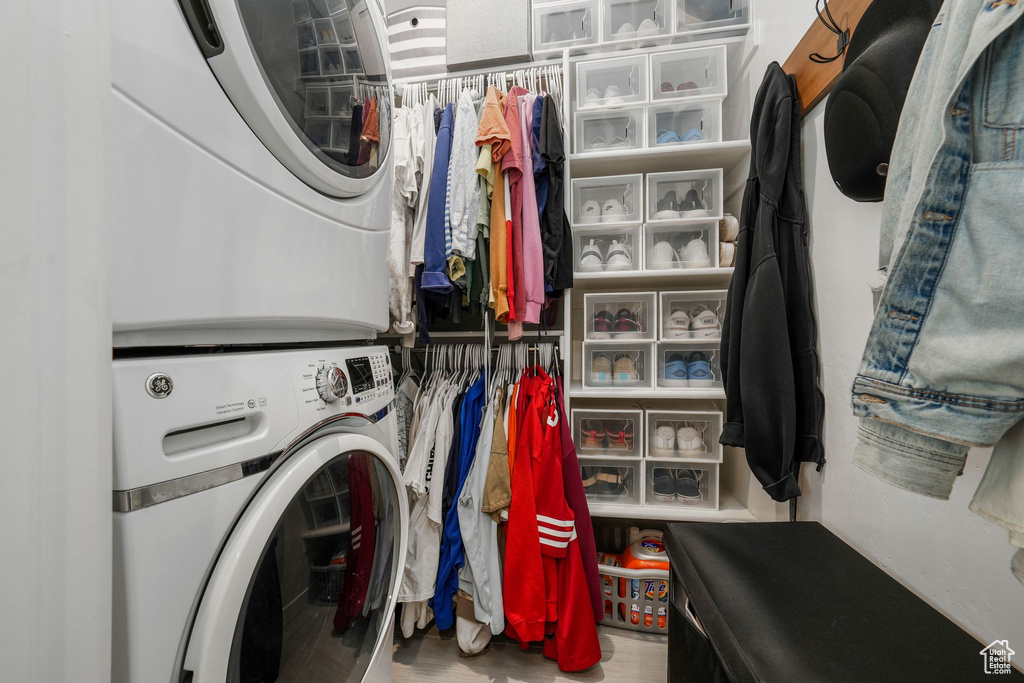 Washroom featuring stacked washing machine and dryer and wood finished floors