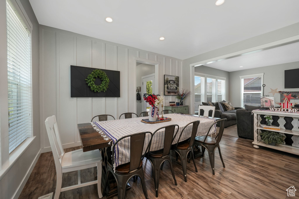 Dining area with wood finished floors, a decorative wall, and recessed lighting