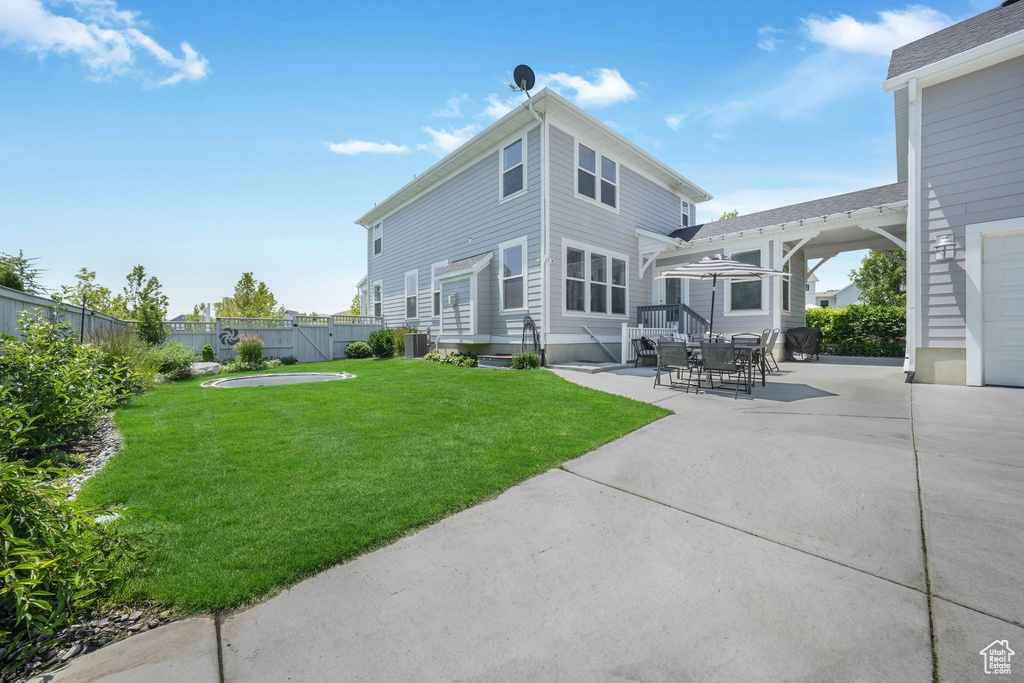 Rear view of house with a fenced backyard and a patio