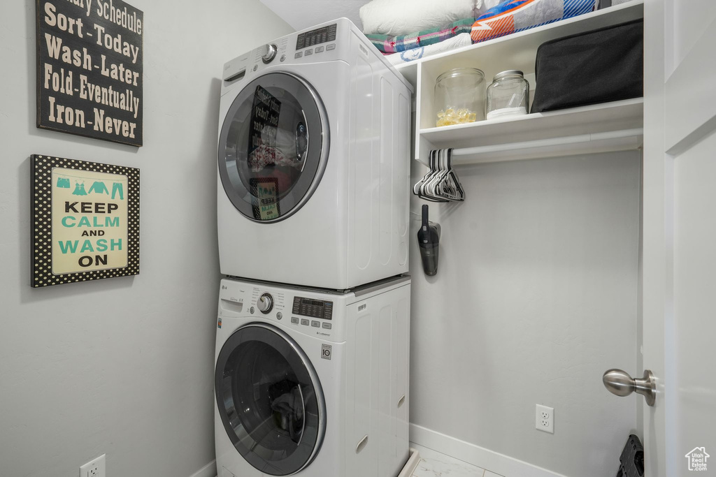 Laundry room with stacked washer / dryer and marble look tiles