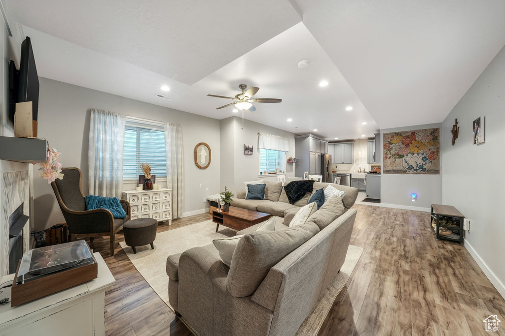 Living room featuring recessed lighting, light wood-style floors, a ceiling fan, and a fireplace