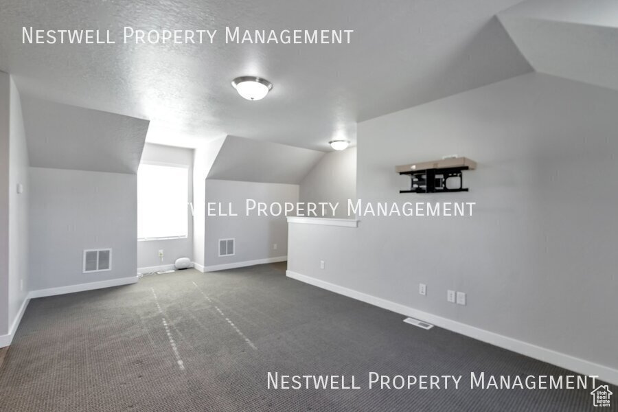 Bonus room with vaulted ceiling and carpet