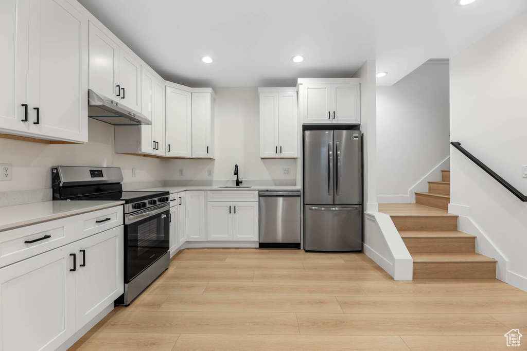 Kitchen featuring appliances with stainless steel finishes, under cabinet range hood, recessed lighting, white cabinets, and light countertops