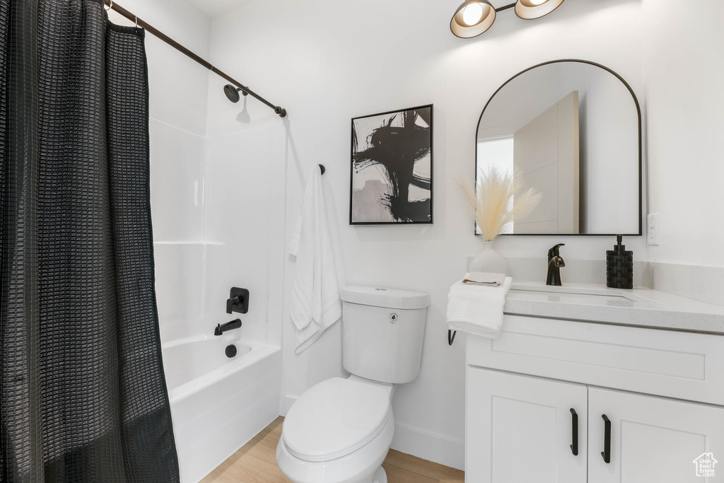 Bathroom with shower / bath combo with shower curtain, vanity, and wood finished floors