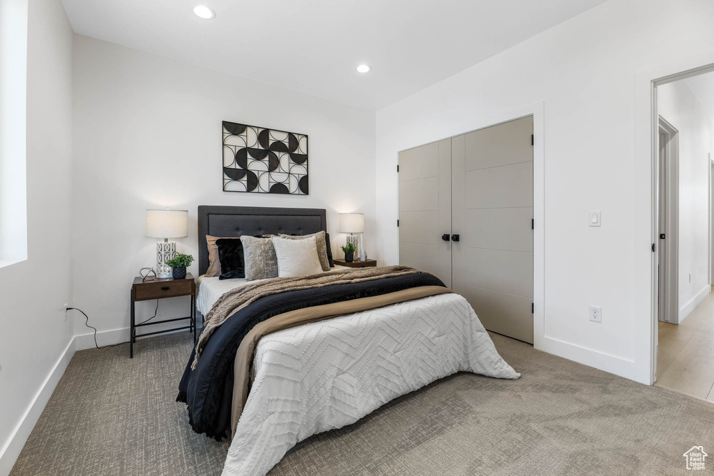 Carpeted bedroom with recessed lighting and a closet
